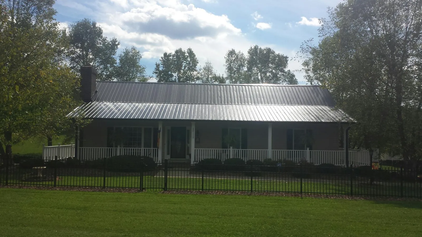 Gray metal roof on a brick ranch with a full width front porch — Gutter Guard Installation work by our crew in Courtland