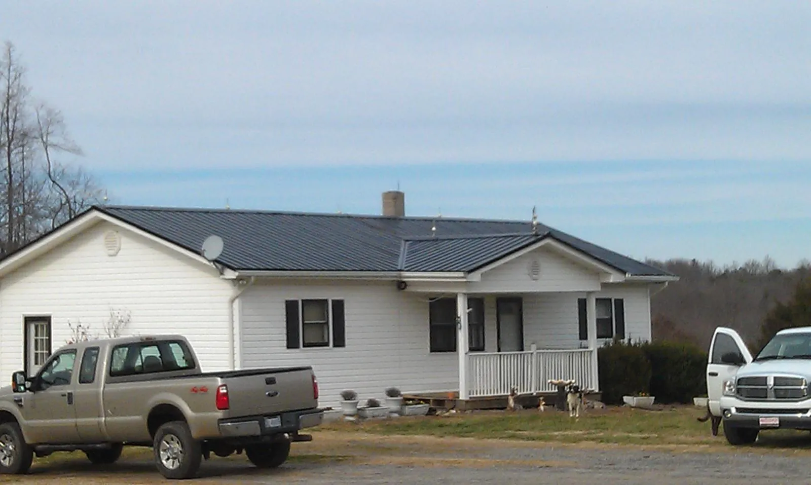 Finished dark metal roof on a white ranch home with work trucks parked in Courtland